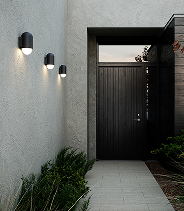 Modern outdoor wall lights illuminating a contemporary home entrance at dusk