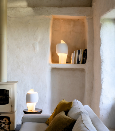 Two sculptural table lamps in warm light, stylishly staged in a minimalist, natural living environment with soft textures.