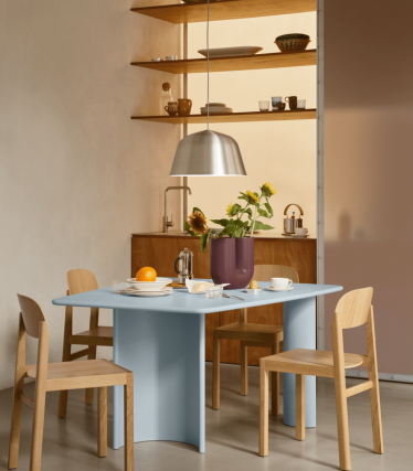 Minimalist dining area with a modern pendant light, wooden shelves and a beautifully set table.