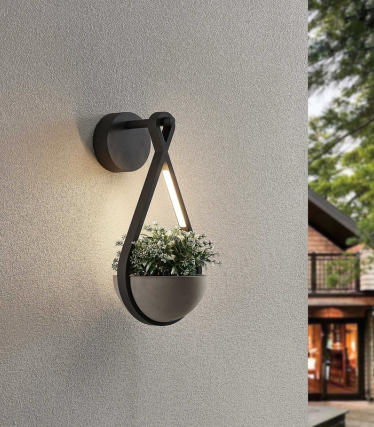 Wall light with integrated planter and warm light on a bright facade.