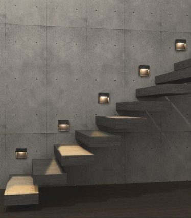 Dark square wall lights line a concrete staircase and illuminate the steps.