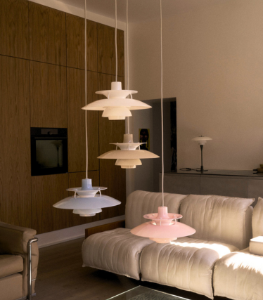 PH 5 pendant lights in white, blue and rose above a cream-coloured sofa in front of an oak wood wall.
