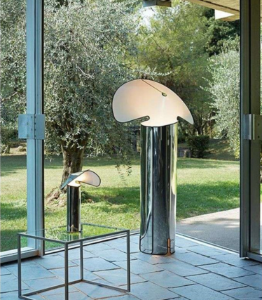 Two glossy floor lamps with curved, leaf-shaped shades in front of a window overlooking the garden.