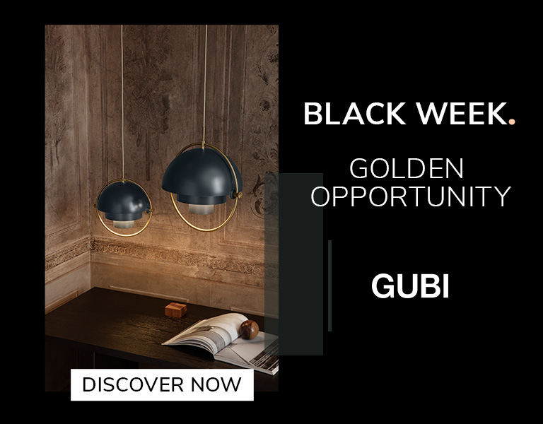 Two modern pendant lamps with dark blue domes and gold accents hanging above a wooden desk in a warmly lit, ornate room. Text reads: ‘Black Week. Golden Opportunity. GUBI.’ A button says ‘Discover Now.